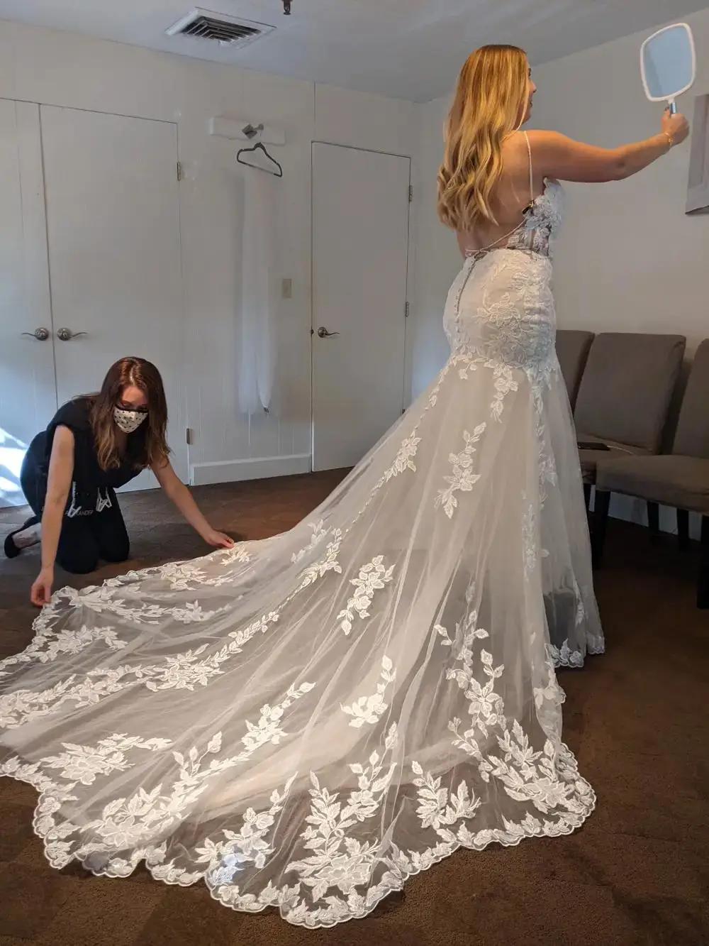 Bride in lace wedding dress with long train and bridal stylist