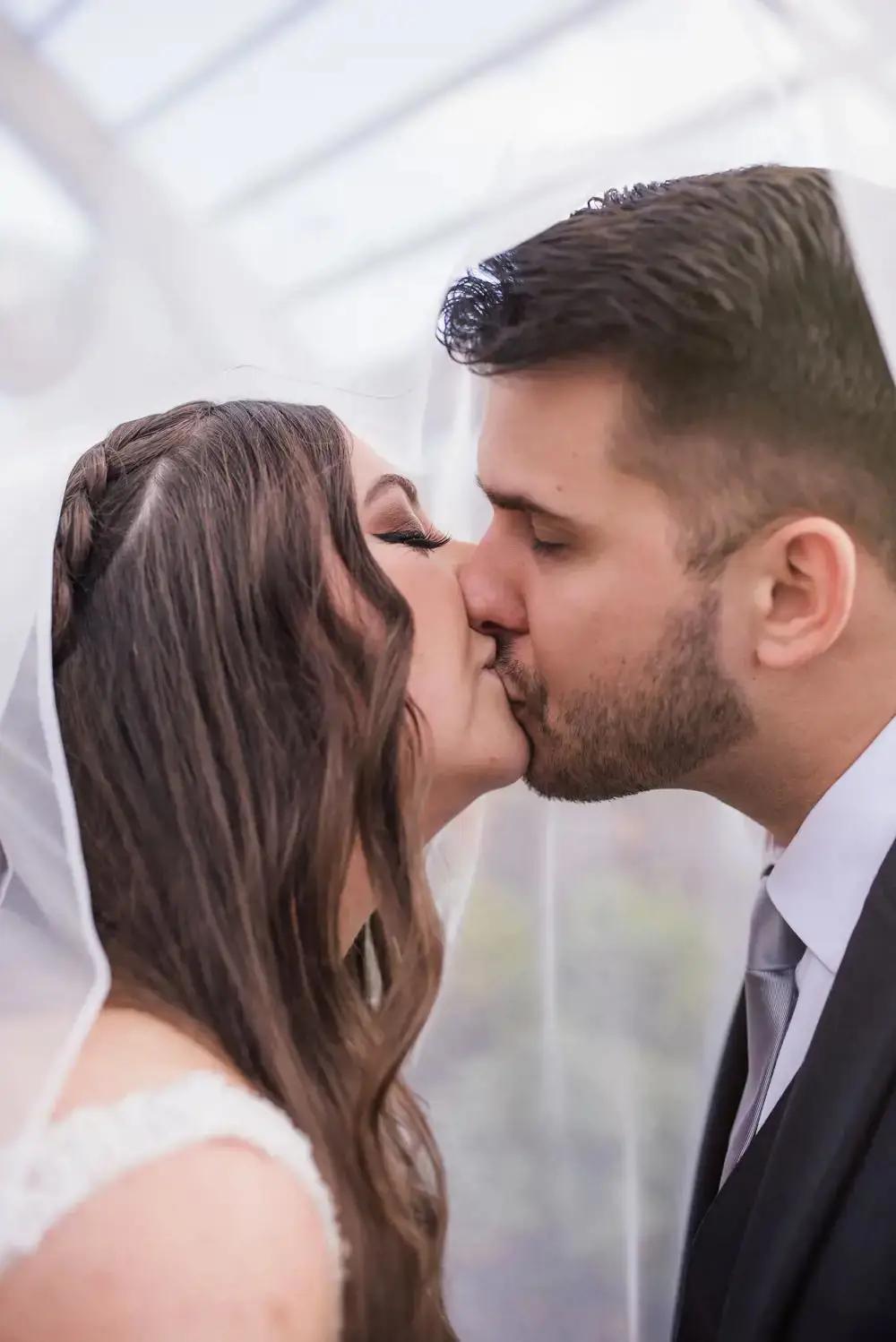 bride & groom kiss under veil shot